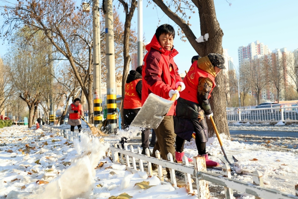 图为陈奇峰带领义工清理道路积雪