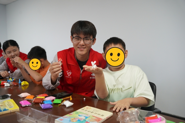 图为青年志愿者和孩子展示粘土作品